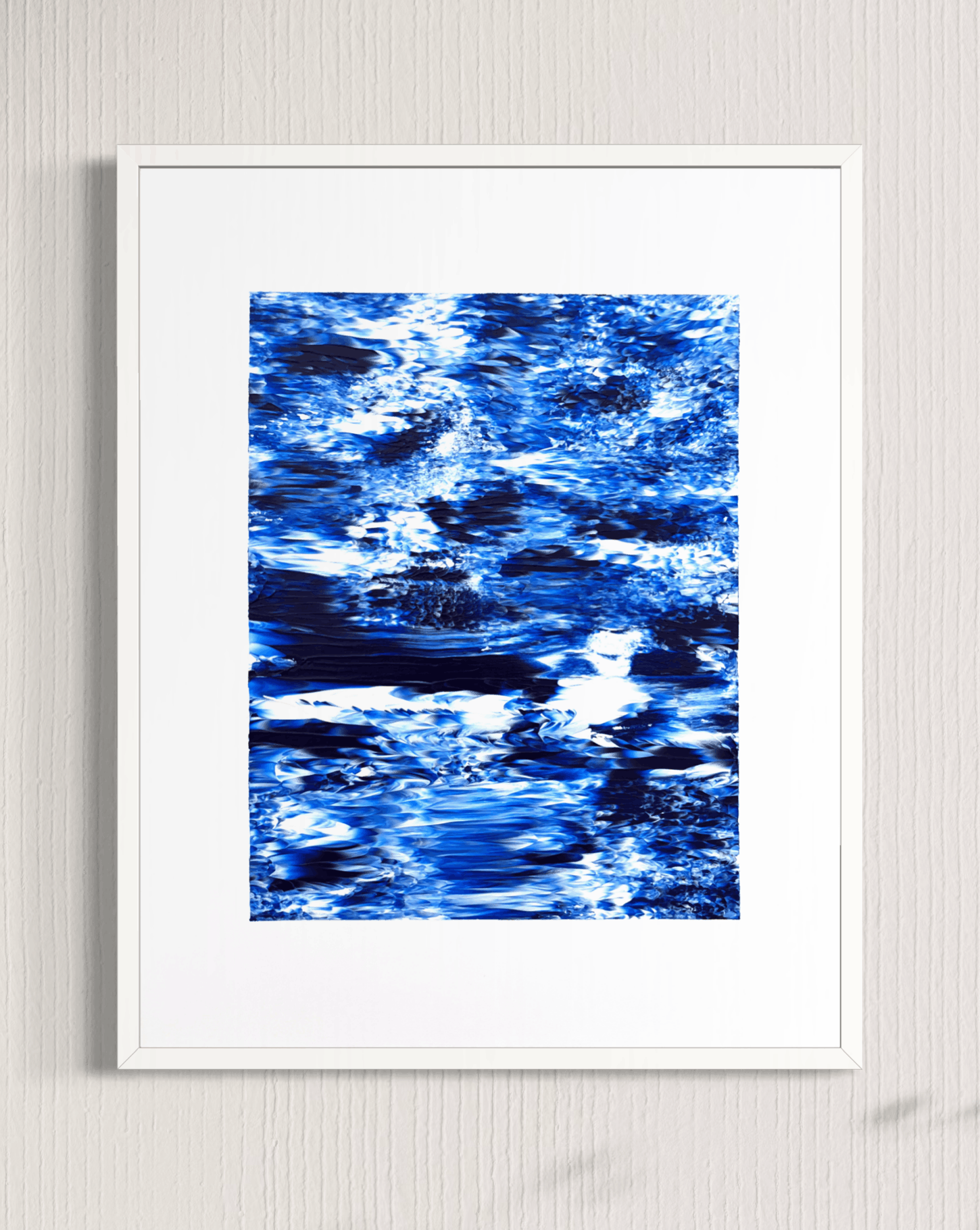 A framed abstract art print featuring a textured blue and white water-like pattern, presented in a white frame against a light gray textured wall.