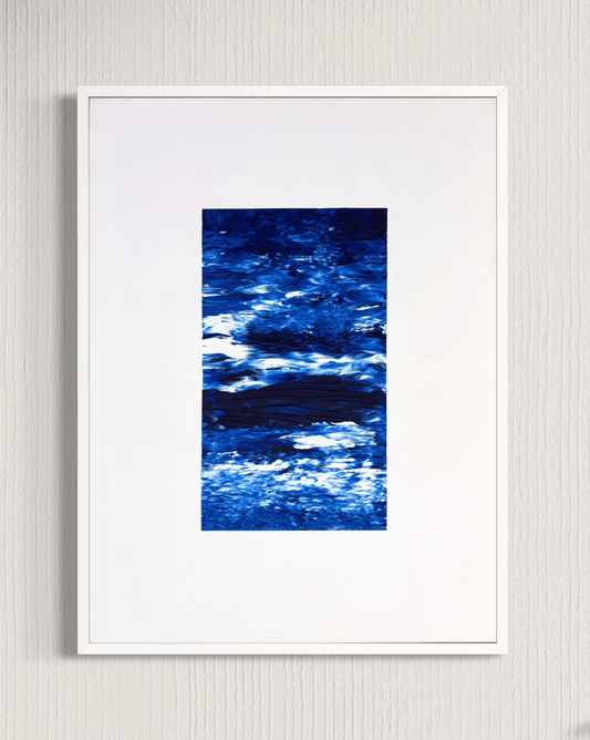 A framed abstract art print featuring textured blue and white brushstrokes, presented in a white frame against a light gray textured wall.