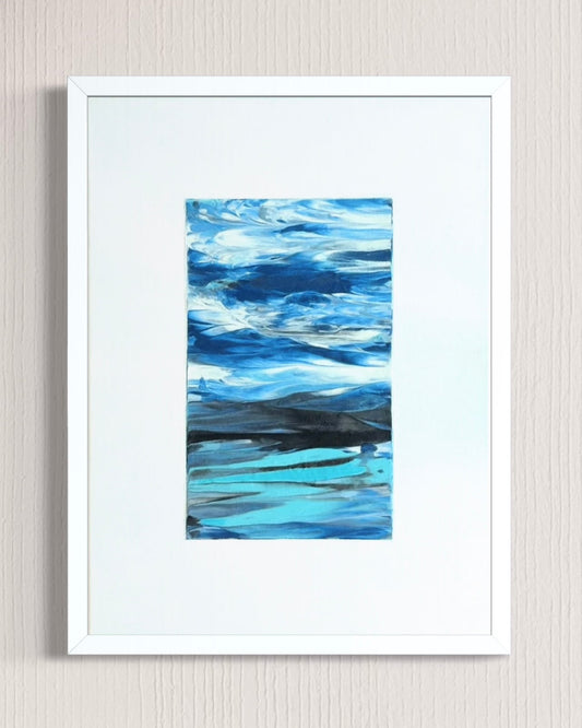 A framed abstract landscape painting featuring shades of blue, teal, and white, presented in a white frame with a wide white mat against a light beige textured wall.
