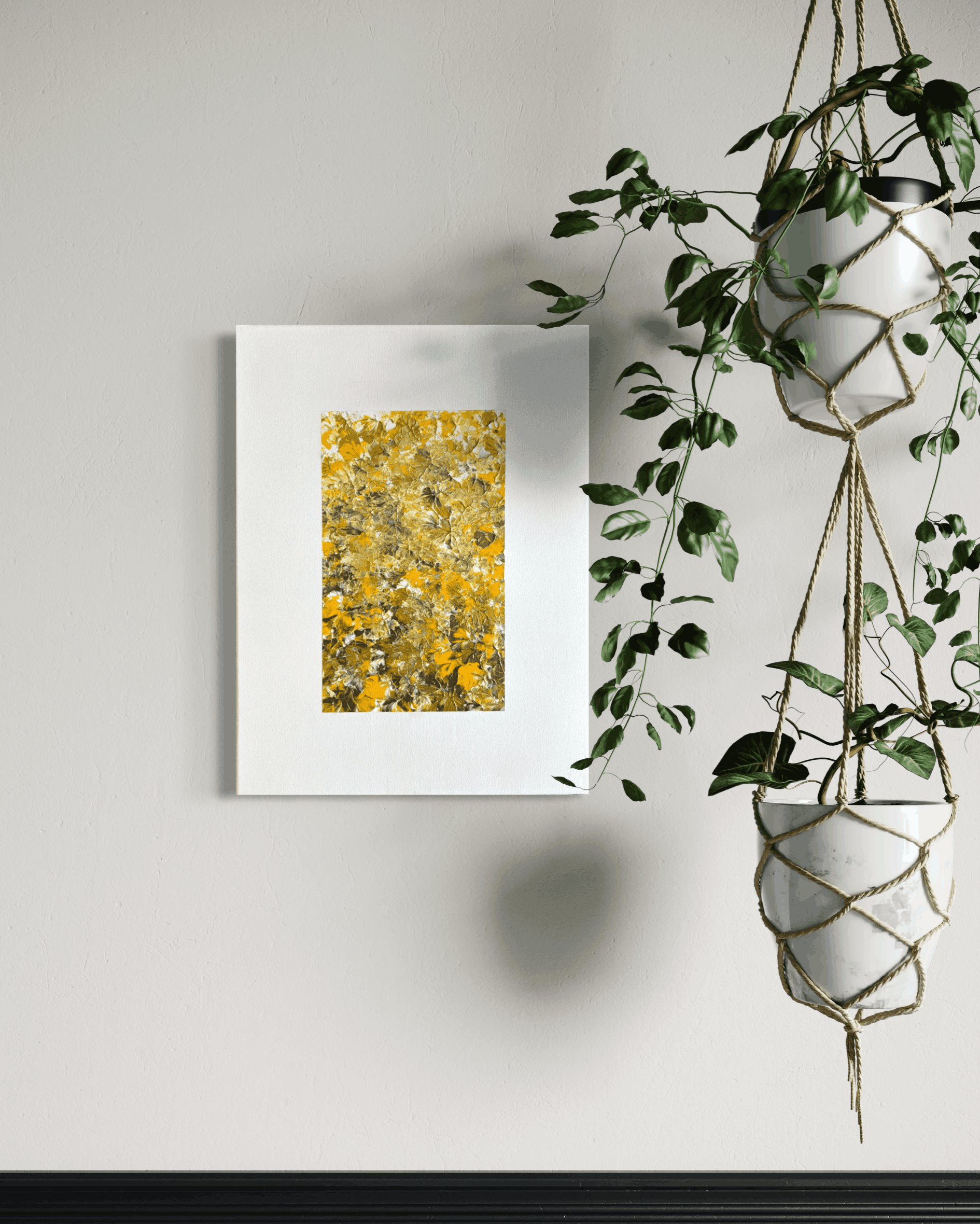A framed abstract art print featuring a textured yellow and gold floral pattern, displayed on a light gray wall next to hanging green houseplants.