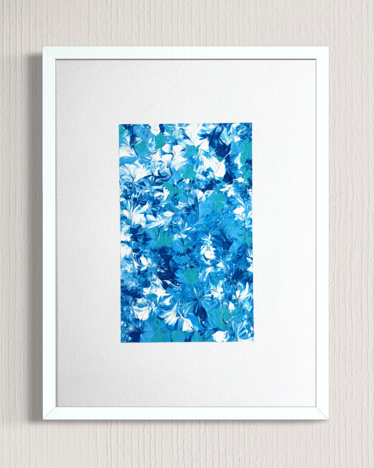 A framed abstract art print featuring a vibrant blue and white floral pattern, presented in a white frame with a white mat against a light gray textured wall.
