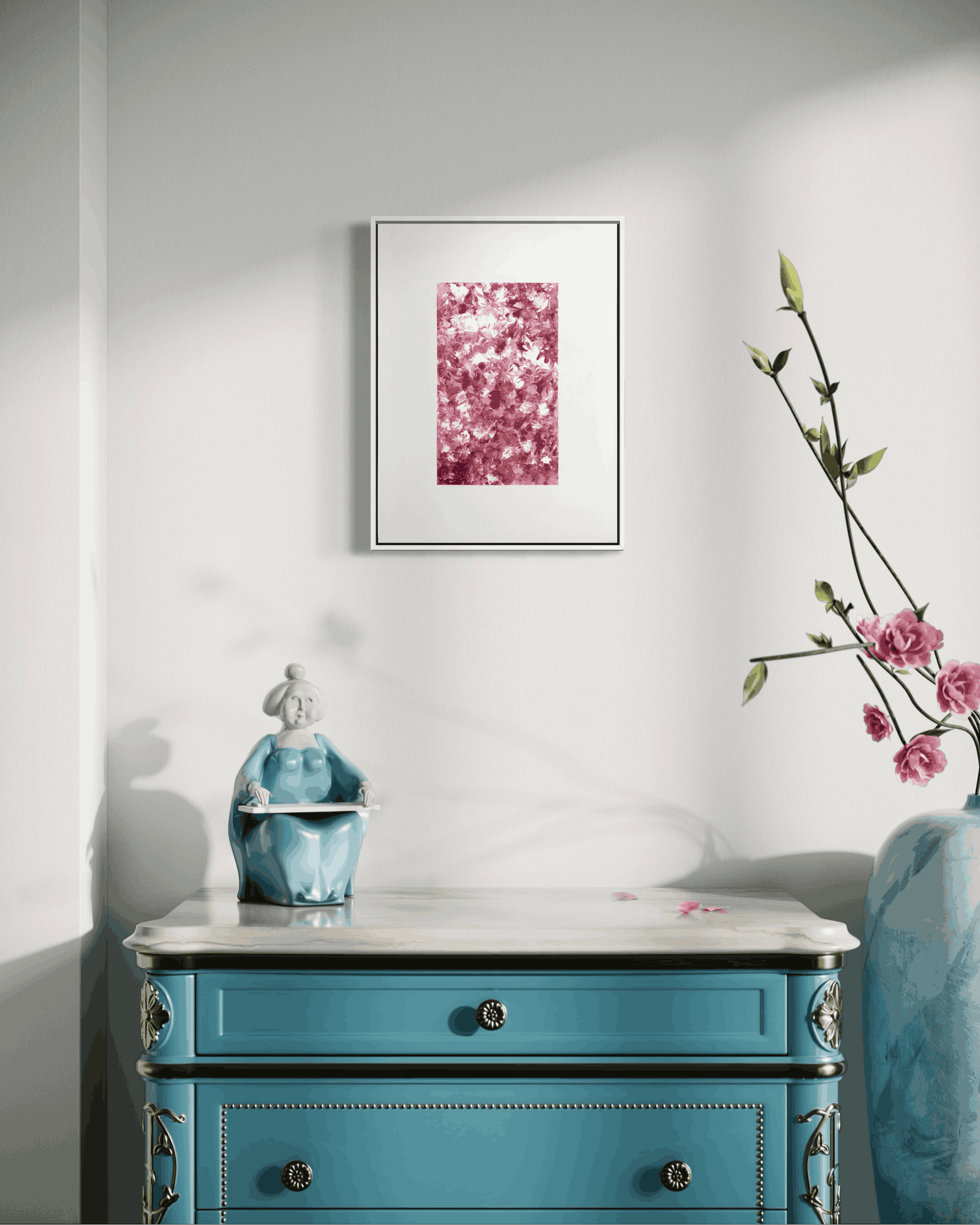 A framed art print featuring a pink and red floral pattern, displayed on a white wall above a turquoise blue wooden dresser with a marble top. A small blue figurine sits on the dresser, and a tall vase with pink flowers is on the right.
