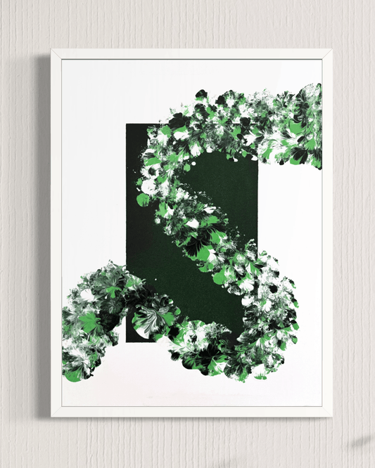 A framed abstract art print featuring a bold black and white background with a large green 'S' shape formed by textured, leaf-like brushstrokes, displayed on a light gray wall.