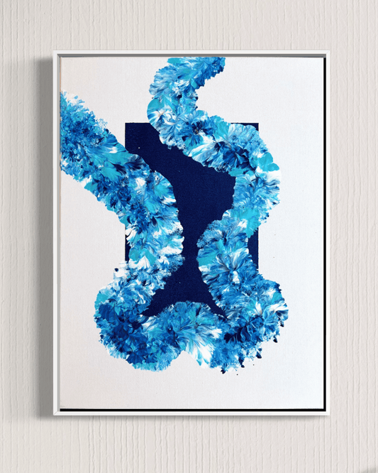 A framed abstract art print featuring a textured blue floral or coral-like pattern around a dark navy X-shaped center, mounted on a light beige textured wall.