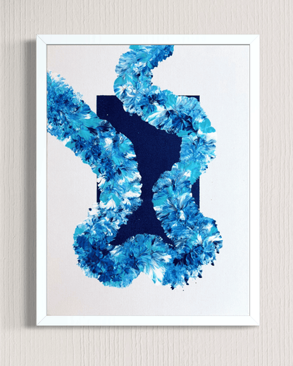 A framed abstract art print featuring a textured blue floral or coral-like pattern around a dark navy central shape, set against a white background and mounted on a light beige wall.