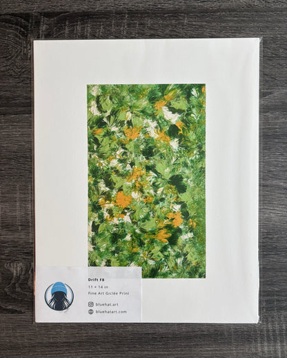 A flat-lay photograph of a matted art print on a dark wood background. The print features a textured green and yellow floral painting surrounded by a wide white mat border.