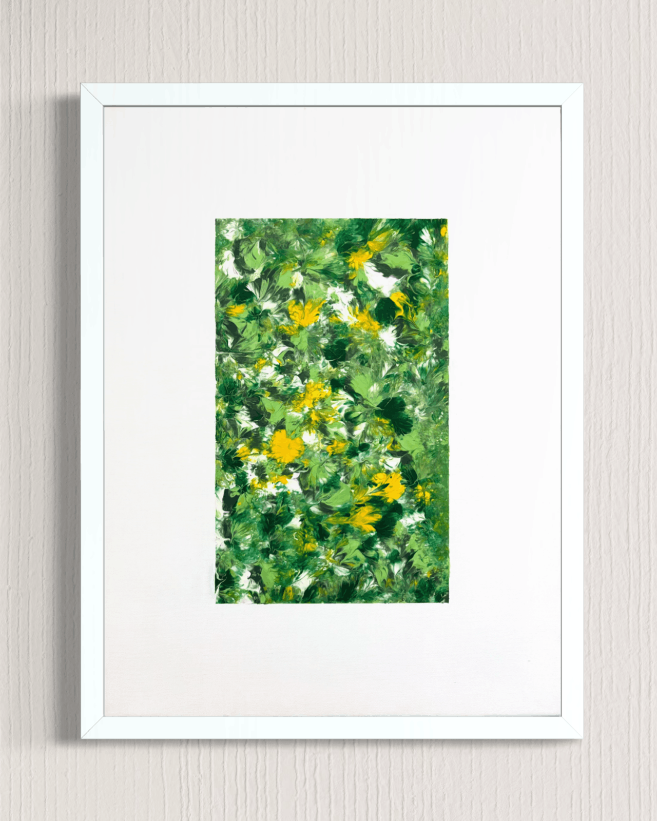 A framed art print featuring an abstract green and yellow floral pattern, presented in a white frame with a white mat against a light gray textured wall.