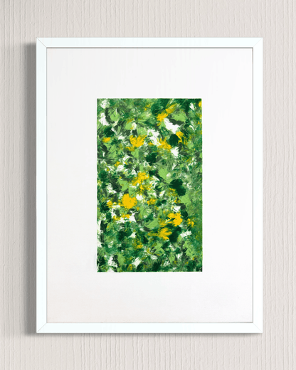 A framed art print featuring an abstract green and yellow floral pattern, presented in a white frame with a white mat against a light gray textured wall.