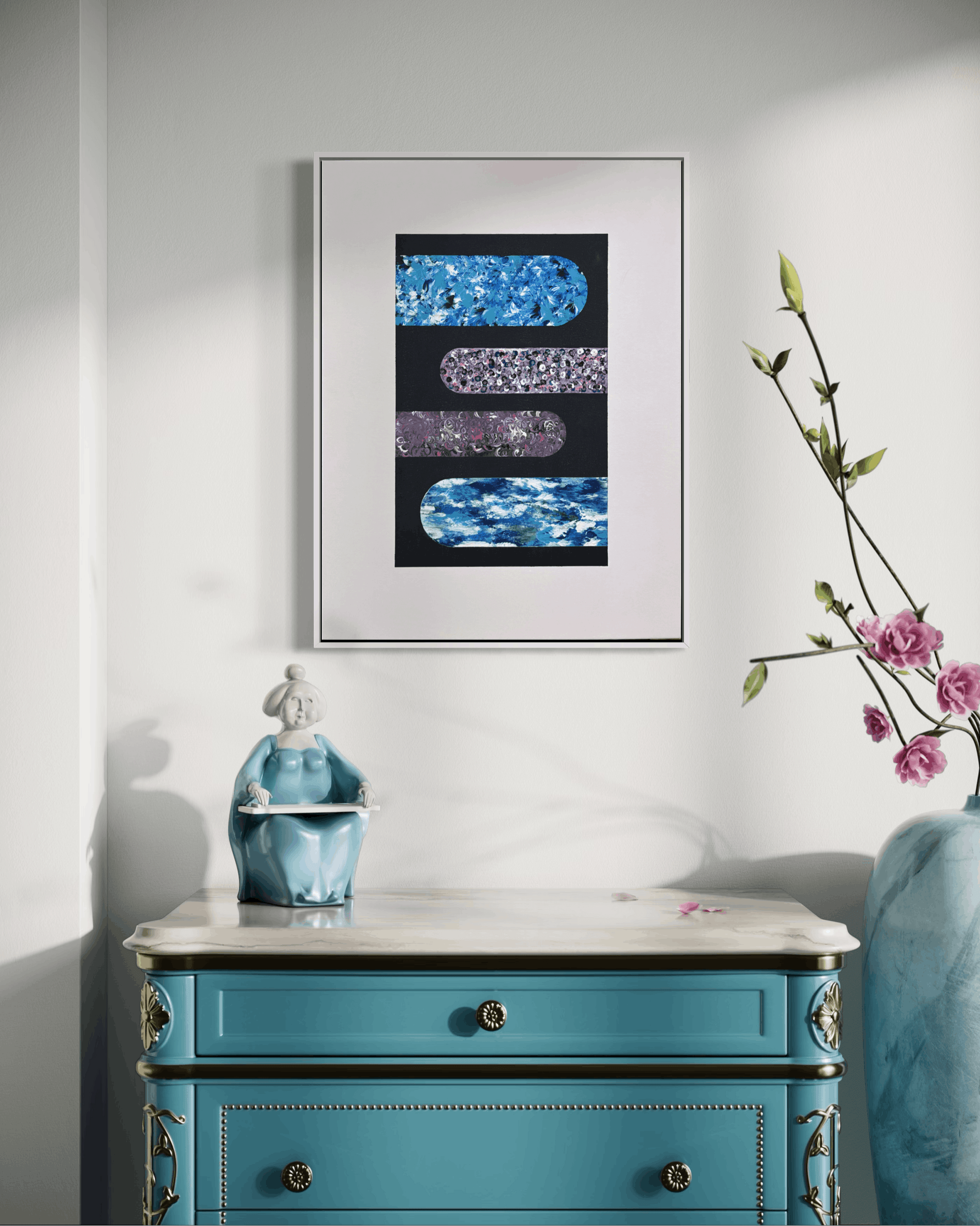A framed abstract art print featuring textured blue, purple, and silver horizontal bars on a black background, styled in a room above a turquoise console table with a vase of pink flowers.