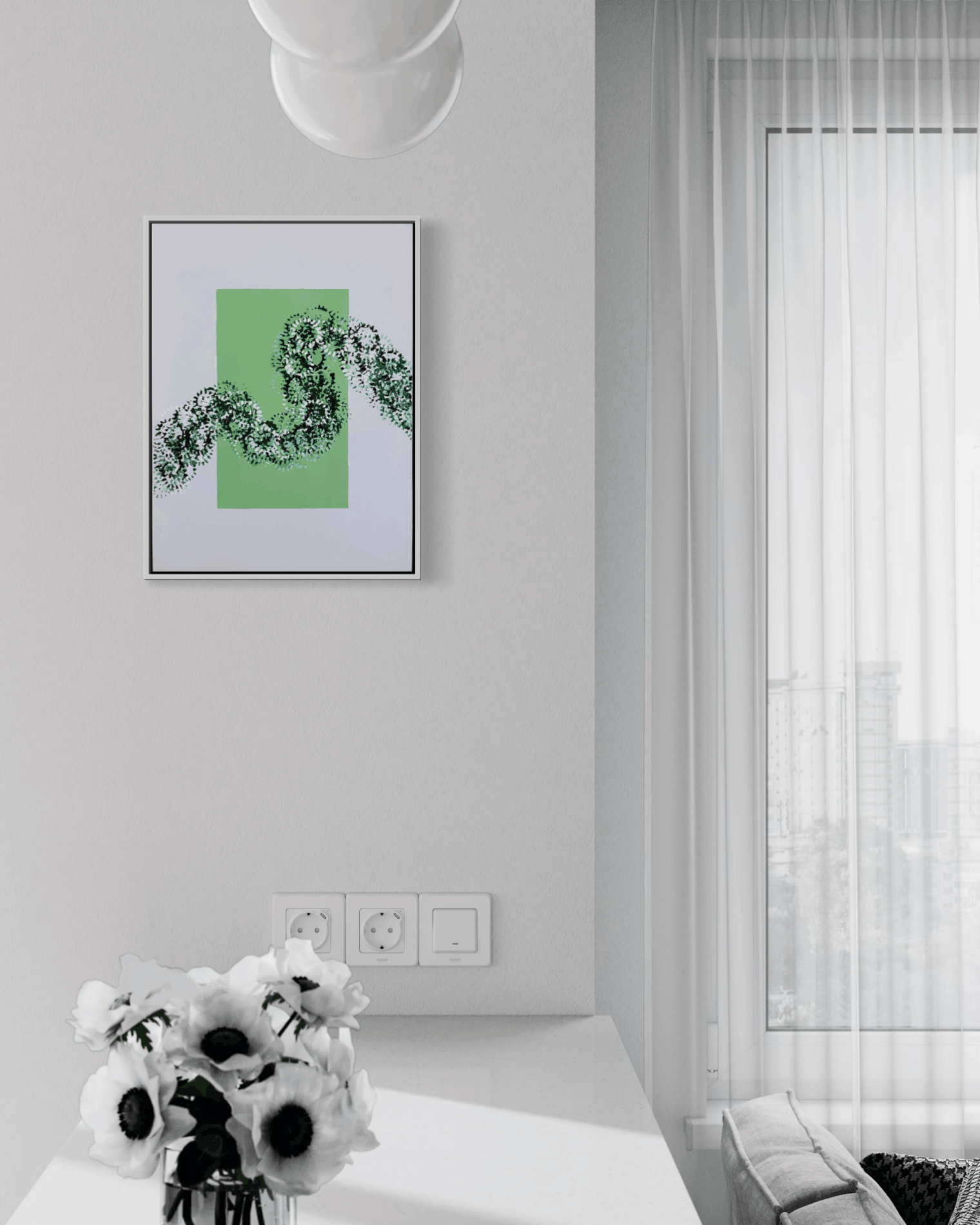 A framed abstract art print featuring a green square and black floral line art, hanging on a light gray wall in a modern, sunlit room with a window and white curtains.