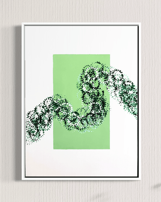 A framed abstract art print featuring a light green rectangular block with a dark green and white textured snake-like pattern crossing it, displayed on a light gray textured wall.