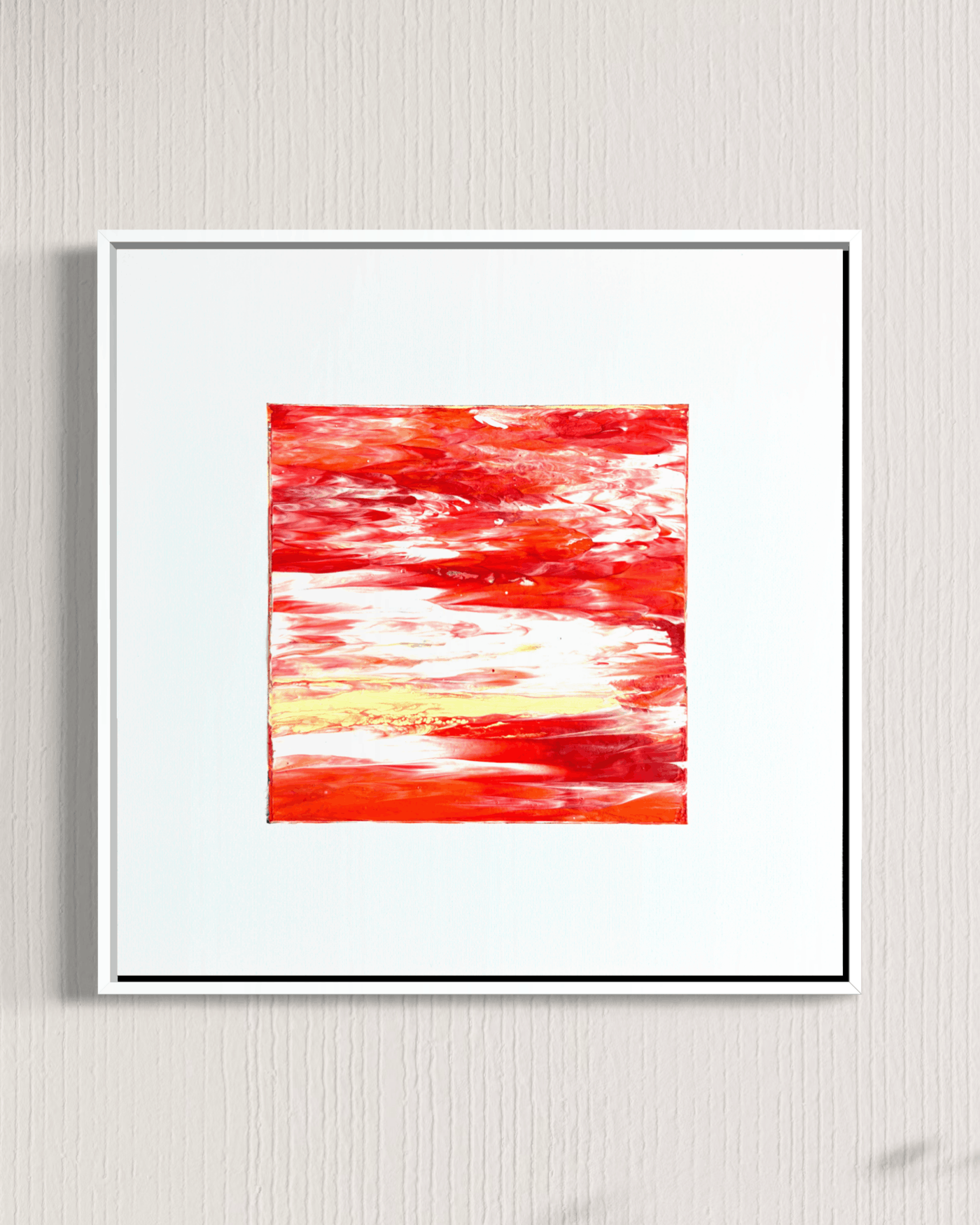 Framed abstract wall art featuring a vibrant red and orange textured painting with white and yellow brushstrokes, set in a white frame against a light gray textured wall.